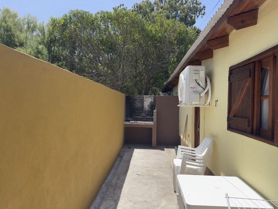 Patio lateral con parrilla y galería de la cabaña para cuatro personas